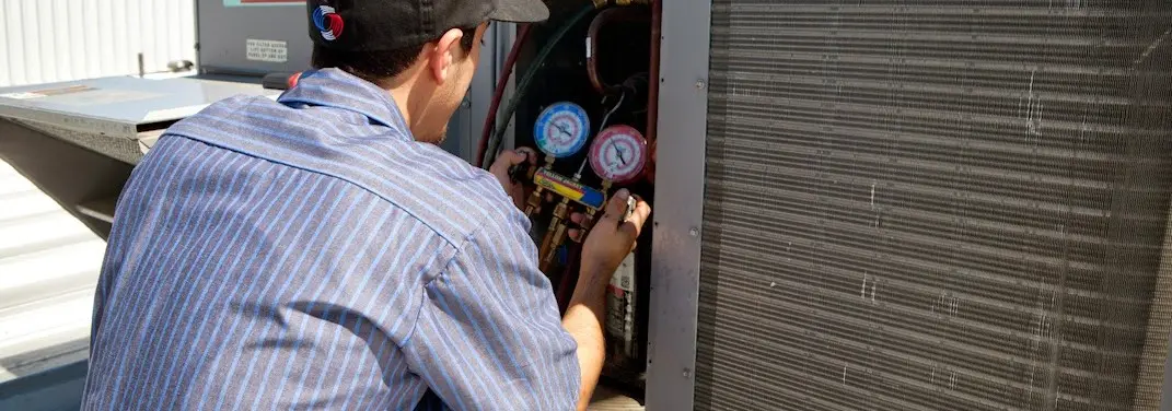 HVAC technician servicing a condenser unit in Bridgton